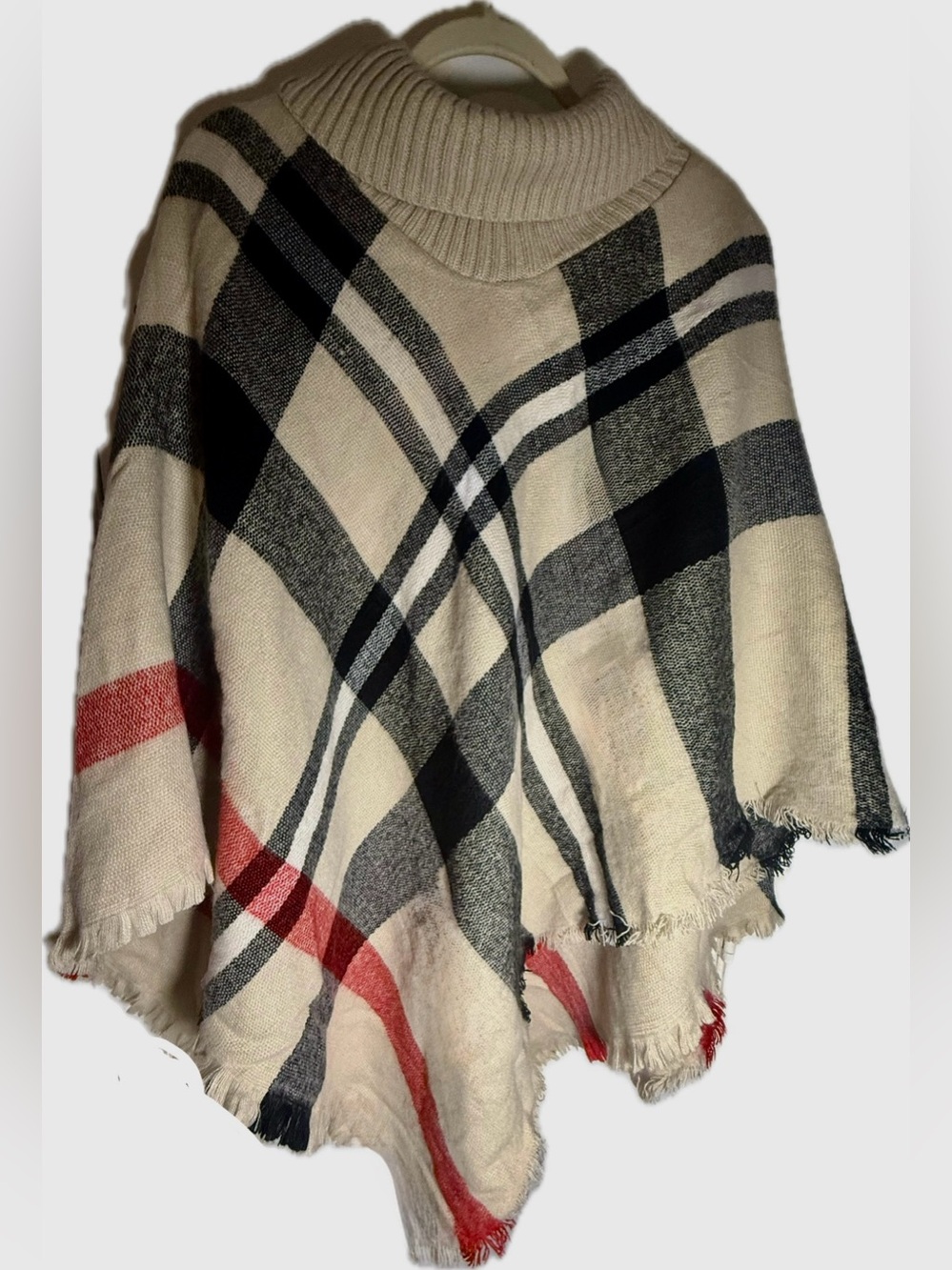 Plaid turtleneck poncho sweater with a tassel fringe hem. One size.